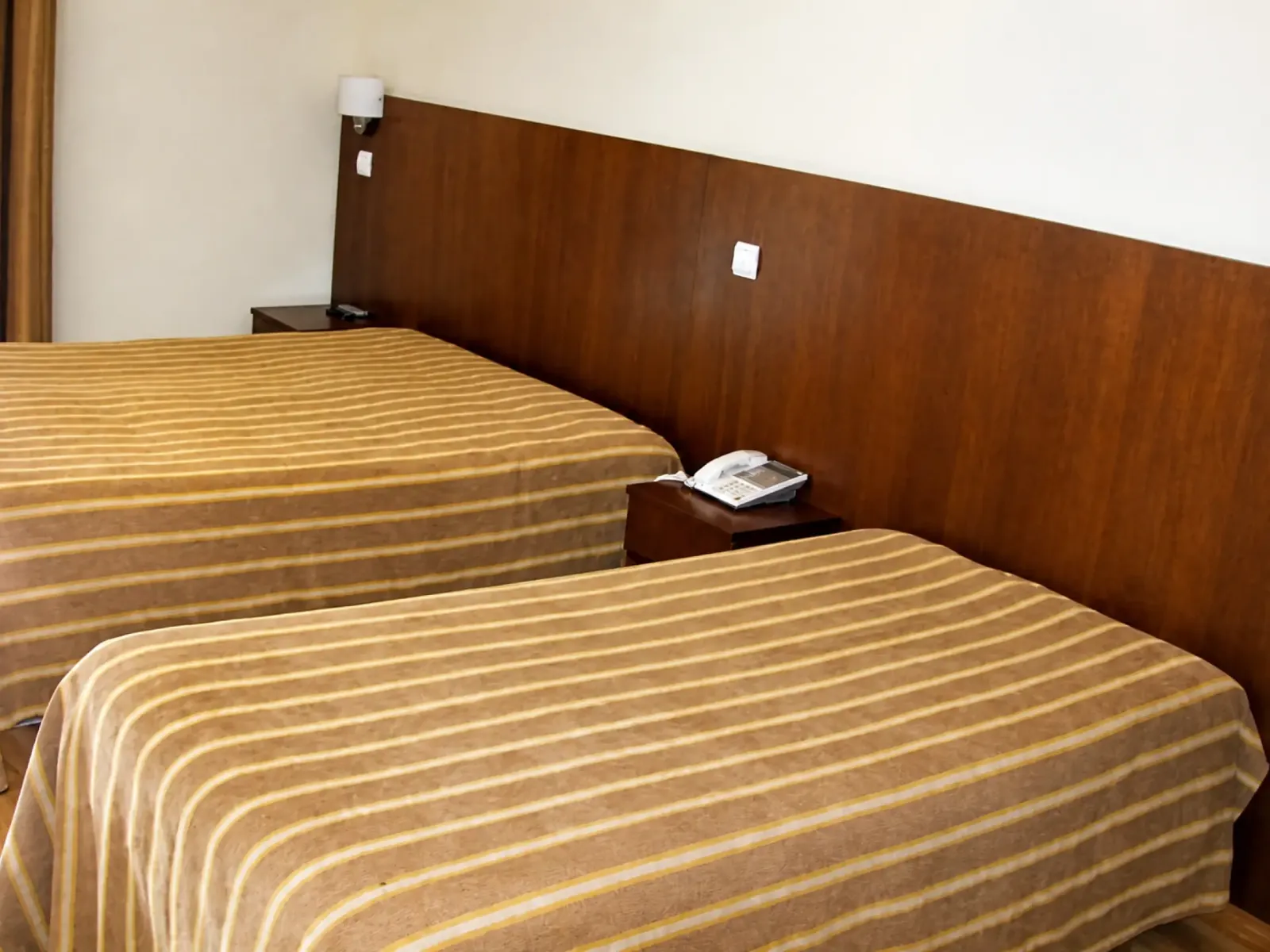 Quarto twin com duas camas separadas e cabeceira de madeira